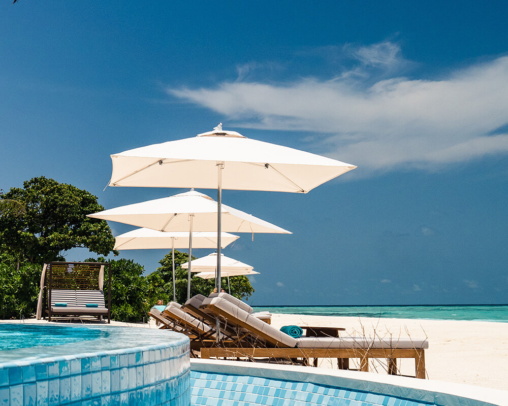 resort stílusú pihenő fehér napernyővel és napozóággyal